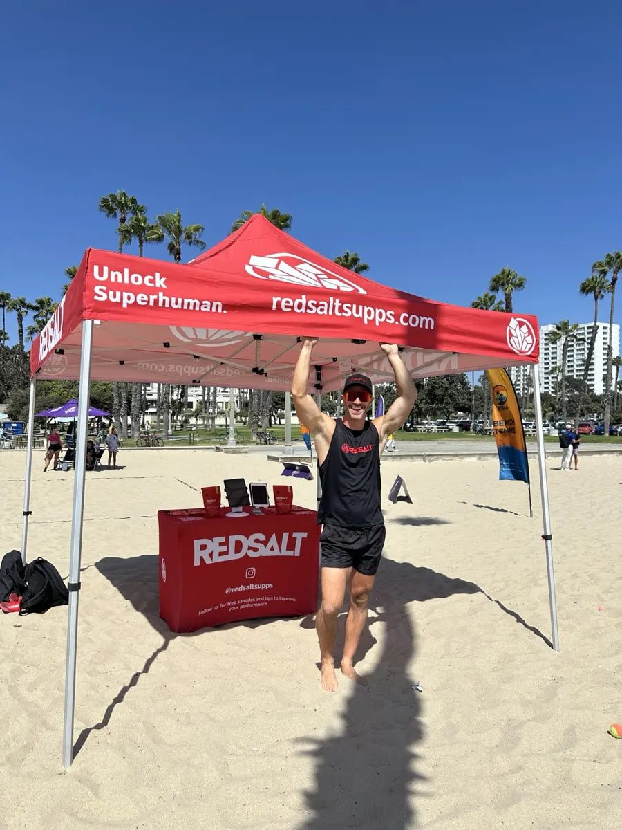 Jacob standing beneath the REDSALT tent at a beach event